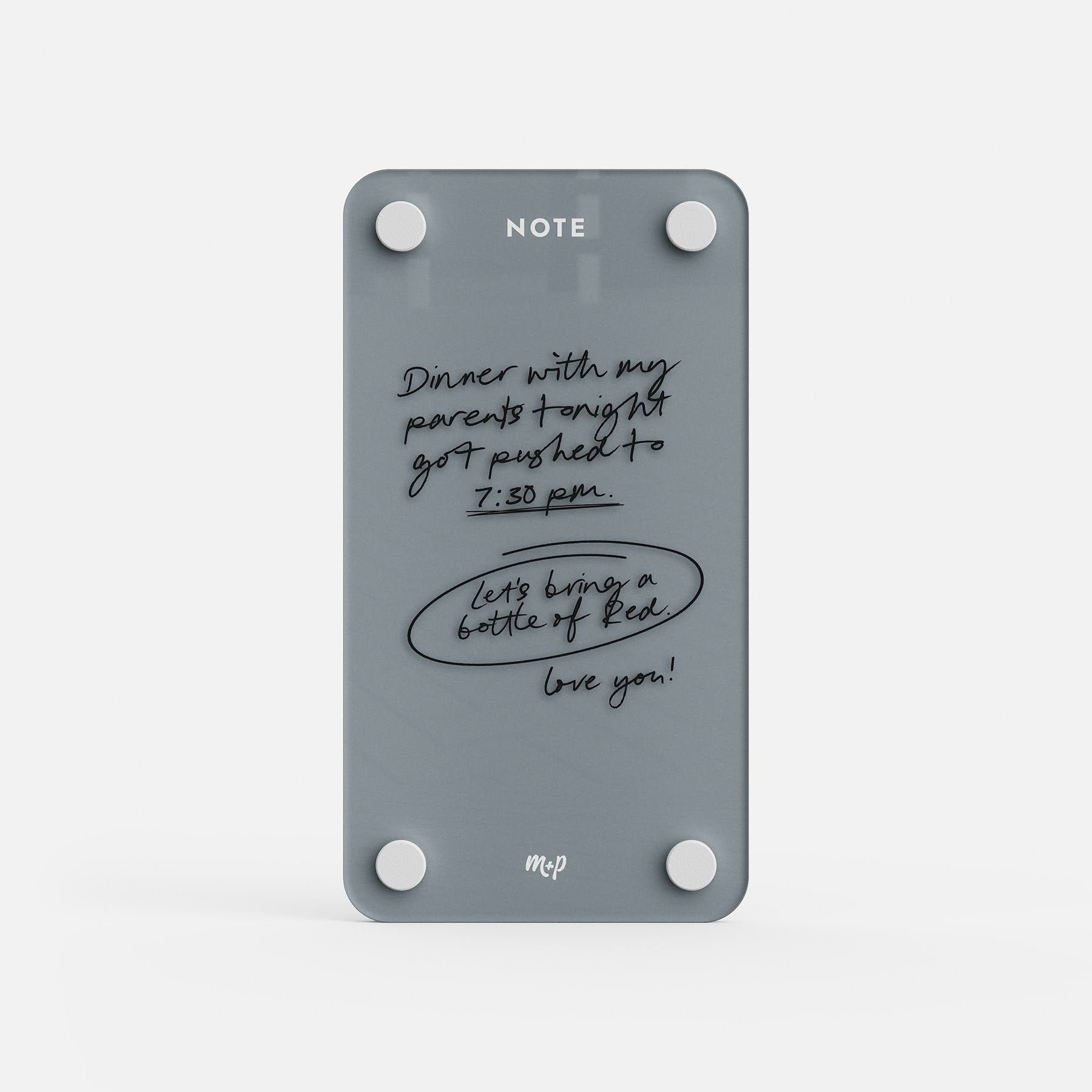 Slate grey tall magnetic acrylic note board with a handwritten message about dinner moving to 7:30